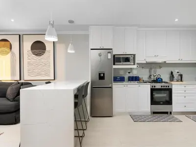 a kitchen with white cabinets and a stainless steel refrigerator at Sandy Shores On Beach - 709 in Strand