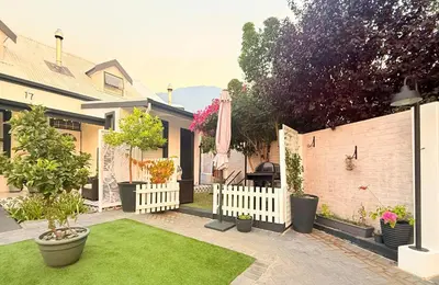 a backyard with a white fence and green grass at Tranquille Haven - serene escape in Franschhoek in Franschhoek
