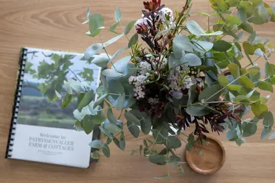 a bouquet of flowers in a vase next to a book at Patryssenvalleij Farm and Cottages in Stellenbosch