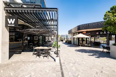 an outdoor patio with tables and chairs and umbrellas at 714 Riverlands - Lux Studio Apartment in Cape Town