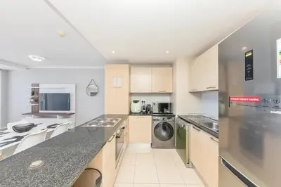 a large kitchen with a washer and dryer at Horizon Bay 303-Oceanfront Apt on Kite Beach with Balcony & Pool in Cape Town