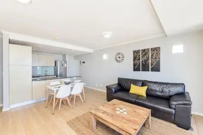 a living room with a black leather couch and a table at Horizon Bay 303-Oceanfront Apt on Kite Beach with Balcony & Pool in Cape Town