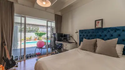 a bedroom with a bed and a desk and a pool at Sunsets' Engina Villa, Sunset Beach in Cape Town
