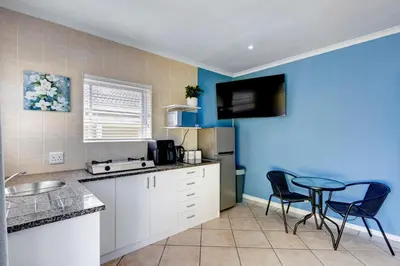 a kitchen with blue walls and a table and chairs at Sea Breeze Kite Dreams 1 in Cape Town