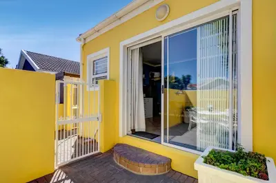 a yellow house with a large sliding glass door at Sea Breeze Kite Dreams 1 in Cape Town