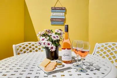 a bottle of wine sitting on a table with wine glasses at Sea Breeze Kite Dreams 1 in Cape Town