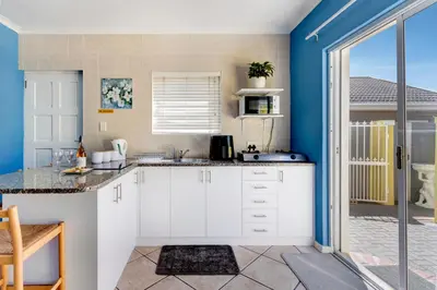 a kitchen with white cabinets and blue walls at Sea Breeze Kite Dreams 1 in Cape Town