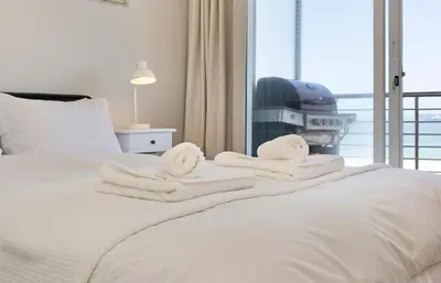 a bedroom with white towels on a bed with a window at Beachfront Apt Kite Beach with Table Mtn View Horizon Bay 501 in Cape Town