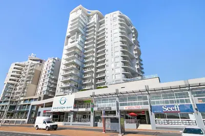 a white car parked in front of a large building at Beachfront Apt Kite Beach with Table Mtn View Horizon Bay 501 in Cape Town