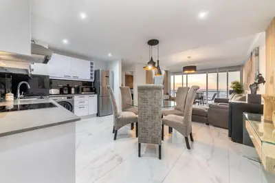 a kitchen and living room with a table and chairs at Beautiful 3 bed apartment with sea views Horizon Bay 502 in Cape Town