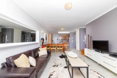 a living room with a couch and a table at Beachfront Bliss with Table Mountain Views Horizon Bay 801 in Cape Town