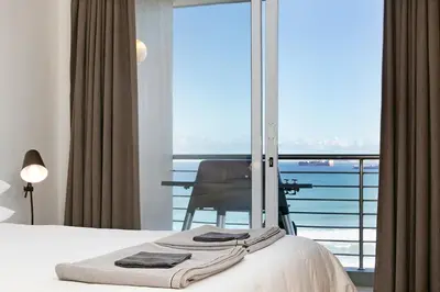 a bedroom with a bed and a view of the ocean at Chic Beachfront Apt with Table Mountain Views Horizon Bay 902 in Cape Town