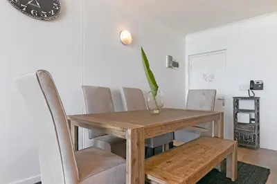 a dining room with a wooden table and chairs at Chic Beachfront Apt with Table Mountain Views Horizon Bay 902 in Cape Town