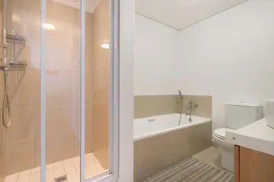 a bathroom with a shower and a toilet and a sink at Chic Beachfront Apt with Table Mountain Views Horizon Bay 902 in Cape Town