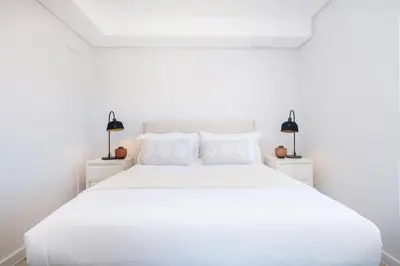 a white bedroom with a white bed and two lamps at 221 Paarl Lux 1 Bdrm Apt with Mountain Views in Paarl