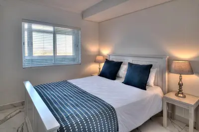 a bedroom with a bed with blue pillows and a window at Horizon Bay 1302 Loadshedding Free APT by HMH in Cape Town