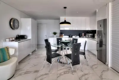 a kitchen with a glass table and black chairs at Horizon Bay 1302 Loadshedding Free APT by HMH in Cape Town