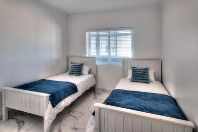 two beds in a white room with a window at Horizon Bay 1302 Loadshedding Free APT by HMH in Cape Town