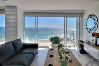 a living room with a couch and a view of the ocean at Horizon Bay 1302 Loadshedding Free APT by HMH in Cape Town
