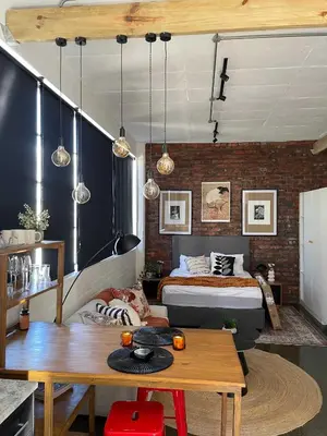 a bedroom with a bed and a table in a room at Trendy Salt River Loft Apartment in Cape Town