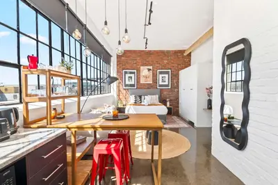 a kitchen and living room with a table and a bed at Trendy Salt River Loft Apartment in Cape Town