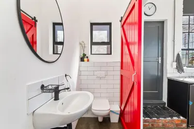 a bathroom with a red door and a sink at Trendy Salt River Loft Apartment in Cape Town
