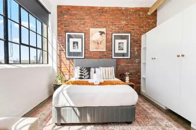 a bedroom with a brick wall and a bed at Trendy Salt River Loft Apartment in Cape Town