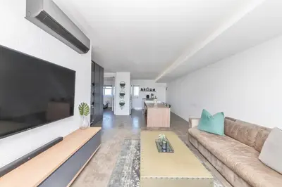 a living room with a couch and a large flat screen tv at Modern Sea View Retreat with Pool & Inverter Horizon Bay 1405 in Cape Town
