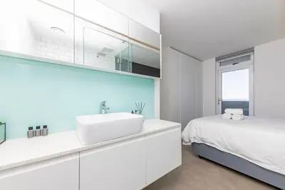 a white bathroom with a sink and a bed at Modern Sea View Retreat with Pool & Inverter Horizon Bay 1405 in Cape Town