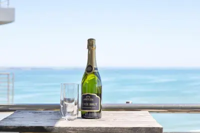 a bottle of wine and a glass on a table at Modern Sea View Retreat with Pool & Inverter Horizon Bay 1405 in Cape Town