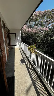 a balcony with a fence and a tree with pink flowers at Homey Central Apartment By ARPA in Stellenbosch
