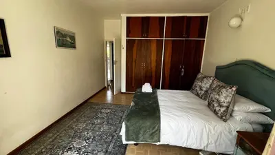 a bedroom with a bed with a green headboard at Homey Central Apartment By ARPA in Stellenbosch