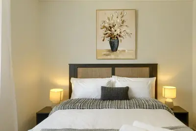 a bedroom with a bed with a vase of flowers at Luxe On Park Century City in Cape Town
