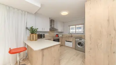 a kitchen with white cabinets and a washing machine at Lagoon Beach Gem 127 Pool, Views & Sea Breeze in Cape Town