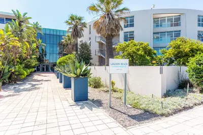 a sign in front of a building with palm trees at Lagoon Beach 124A by CTHA in Cape Town