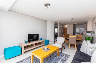 a living room with a couch and a tv at Lagoon Beach 124A by CTHA in Cape Town