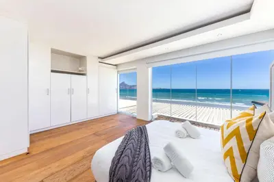 a bedroom with a bed and a view of the ocean at Spinnakers 9 by HMH in Cape Town