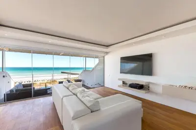 a living room with a white couch and a tv and the ocean at Spinnakers 9 by HMH in Cape Town