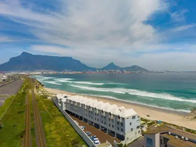 a view of a beach with a building and the ocean at Spinnakers 9 by HMH in Cape Town