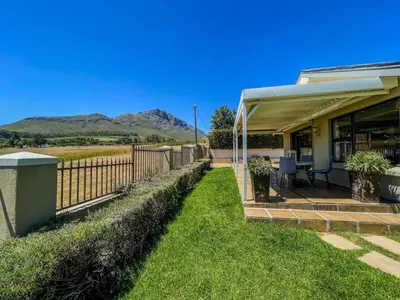 a house with a porch with a fence and mountains at Spacious mountain-view haven in Stellenbosch