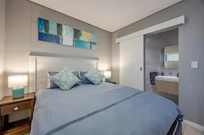 a bedroom with a large bed and a sink at Beach Break Bliss - Cozy retreat with mountain views in Bloubergstrand