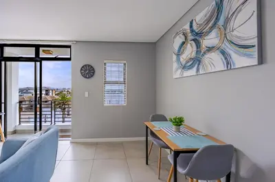 a dining room with a table and chairs at Beach Break Bliss - Cozy retreat with mountain views in Bloubergstrand