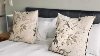 a bed with white sheets and pillows with at 2 Bedroom, 4 Sleeper Hidden Gem Minutes from Blouberg Beach Front in Cape Town