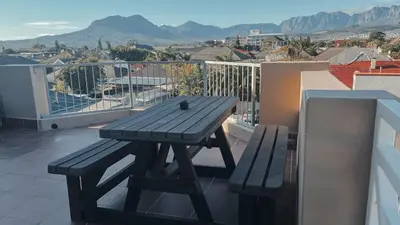 a wooden picnic table on a balcony with a view at Cozy one bed, just a short walk to the beach in Strand