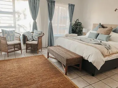 a bedroom with a bed and chairs and a window at Cozy one bed, just a short walk to the beach in Strand