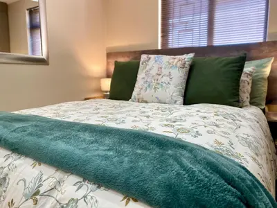 a bed with a green blanket on top of it at Modern Van Riebeeck Park Accomodation in Worcester
