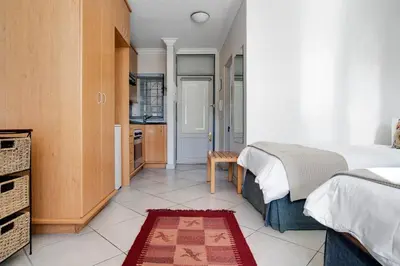 a bedroom with a large bed and a kitchen at The Stellenbosch Hotel in Stellenbosch