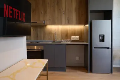 a kitchen with a refrigerator and a table in it at Riverlands Luxury Apartments by City Club in Cape Town