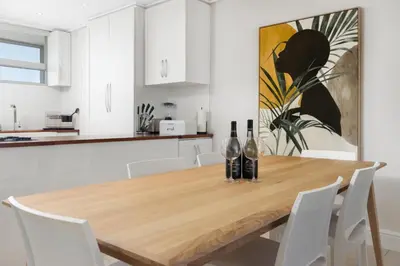 a kitchen with a wooden table with two bottles of wine at Ashley On Beach 1104 Prestige Style in Strand