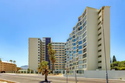a large white building with palm trees in front of it at Ashley On Beach 1104 Prestige Style in Strand